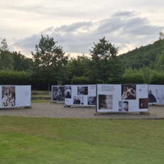 Großformatige Fotografien der Ausstellung „Demenz neu sehen“ auf dem Promenadenplatz in Furth im Wald bei Abendlicht, umgeben von Natur.