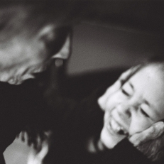 Schwarz-Weiß-Fotografie einer älteren Person, die sanft das Gesicht einer lächelnden jungen Frau in den Händen hält, inniger und emotionaler Moment.
