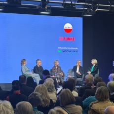 Podiumsdiskussion vor blaunem Hintergrund