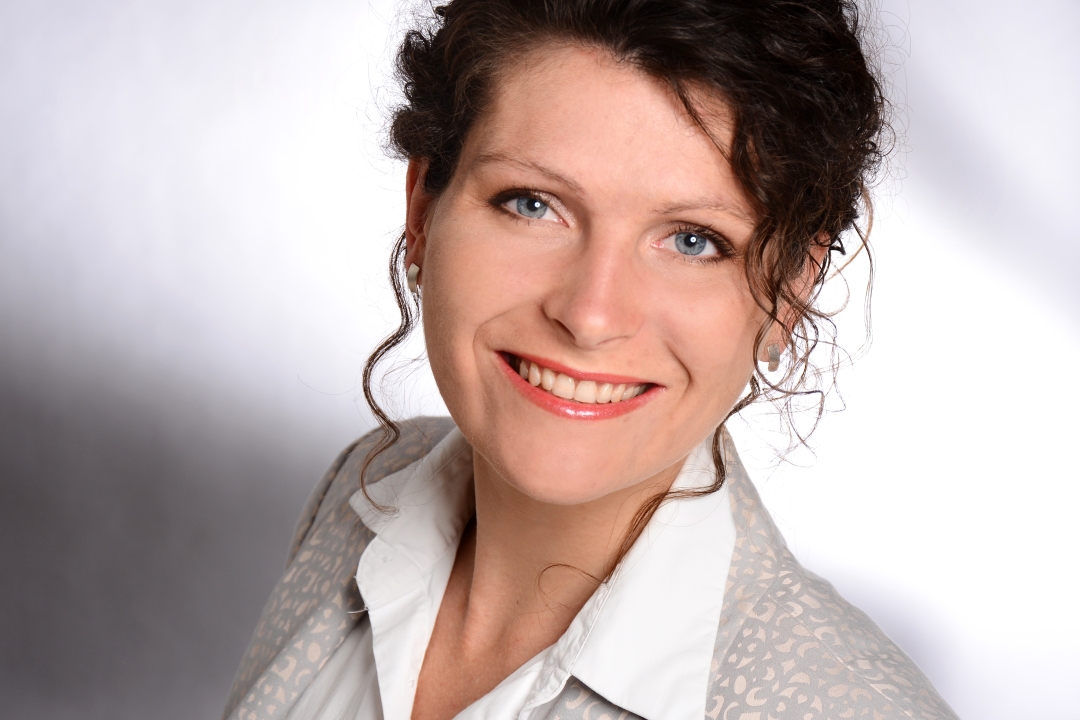 Frau mit dunklem Haar lächelt in die Kamera