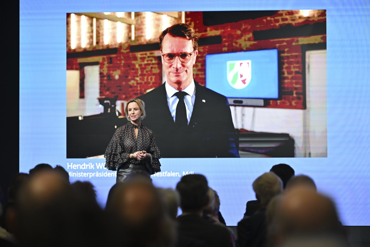 Moderatorin steht vor Leinwand