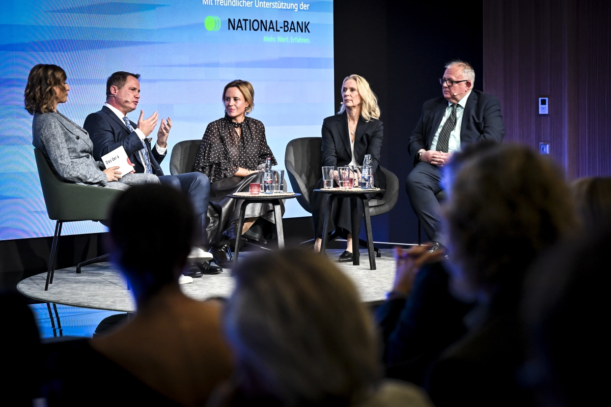 Speaker einer Podiumsdiskussion auf der Bühne unterhalten sich