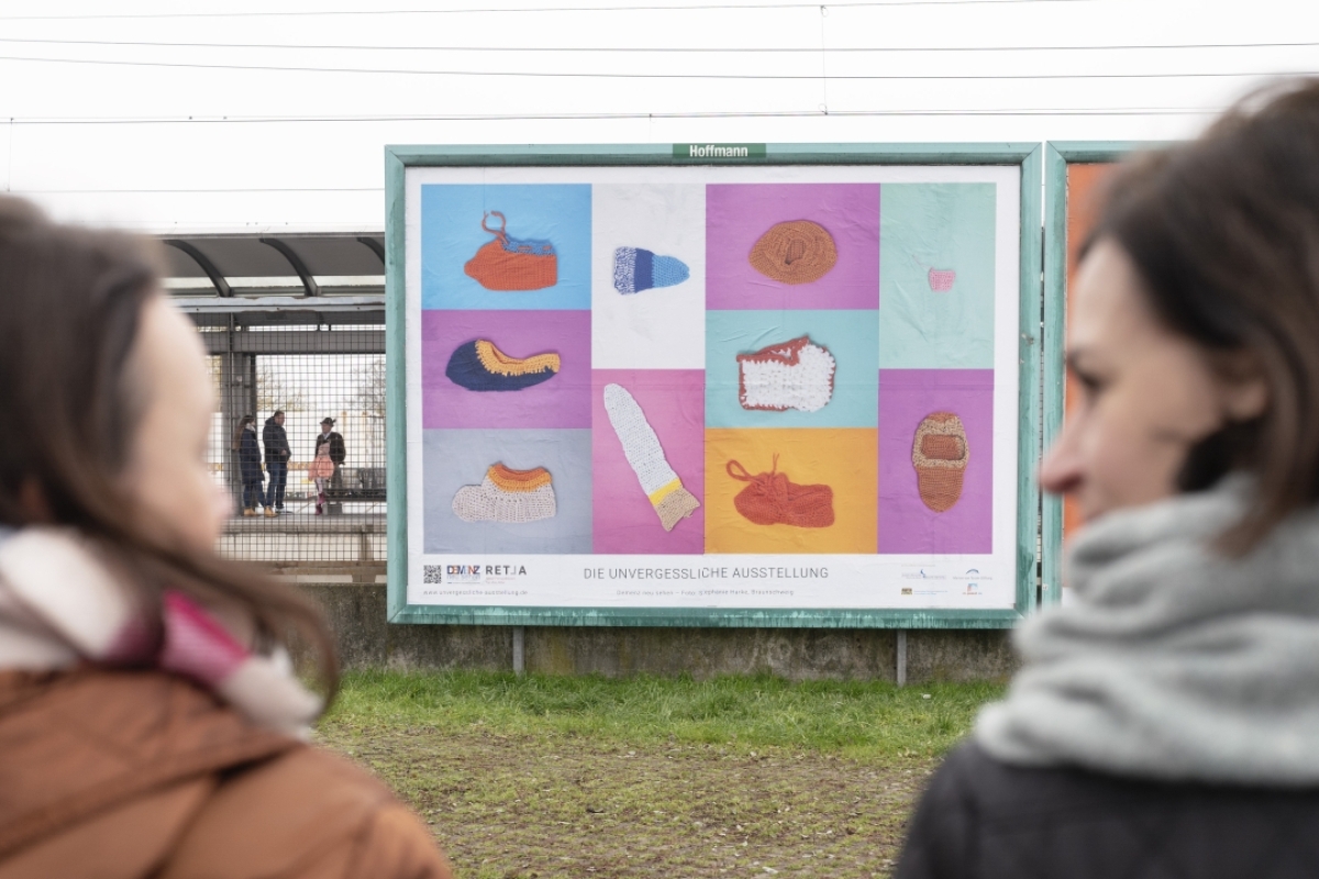 Zwei Frauen schauen zu einem Plakat der unvergesslichen Ausstellung Demenz neu sehen