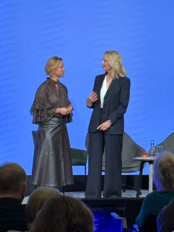 Zwei Frauen stehen auf einer Bühne vor blauem Hintergrund