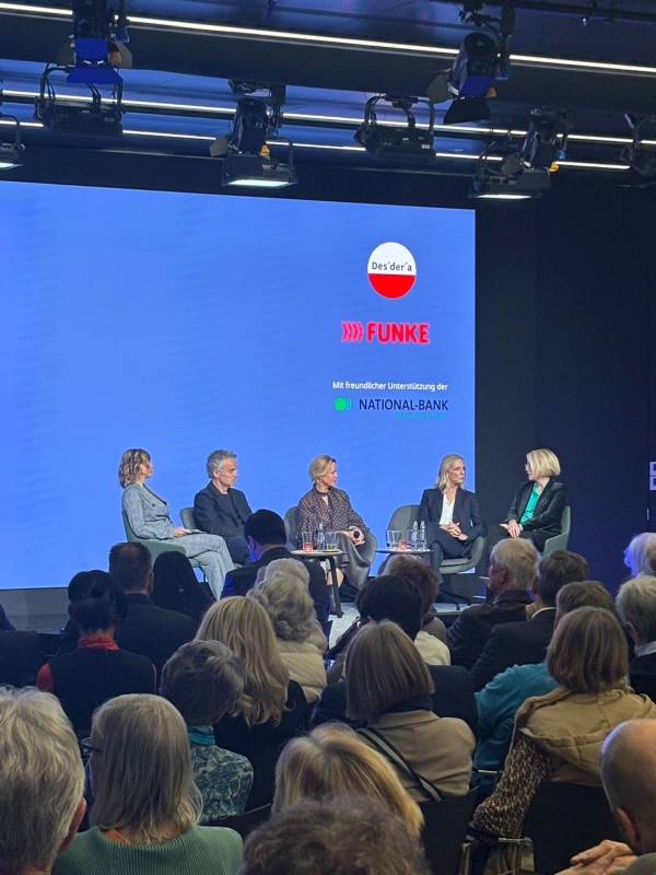 Podiumsdiskussion vor blaunem Hintergrund