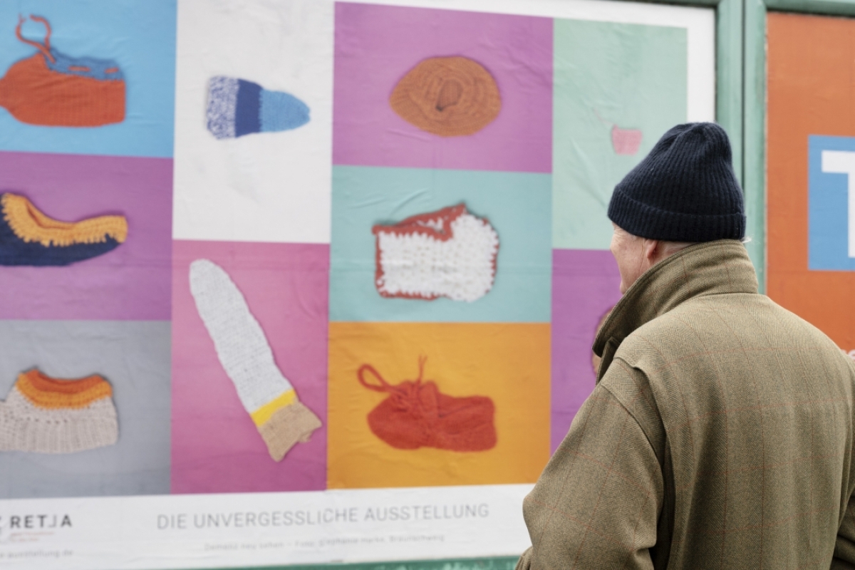 Mann schaut auf Plakat der unvergesslichen Ausstellung Demenz neu sehen