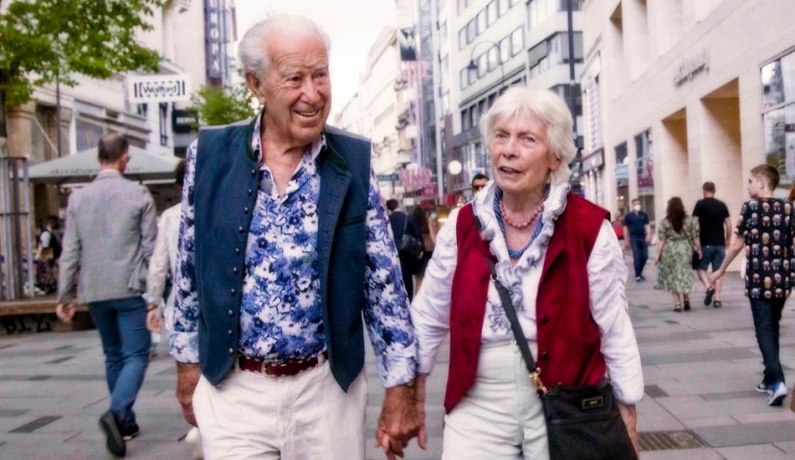 Altes Ehepaar läuft Händchen haltend durch die Stadt