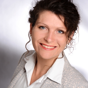 Frau mit dunklem Haar lächelt in die Kamera