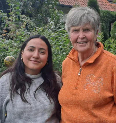 Eine ältere Dame und eine junge Frau lächeln in die Kamera