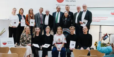 Gruppenfoto von 15 Personen in einem hellen Veranstaltungsraum, einige halten Urkunden oder Auszeichnungen in den Händen, im Hintergrund Logos der Stiftung Katholische Akademie.