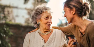 Eine ältere Dame und eine jüngere Frau unterhalten sich glücklich und lächelnd
