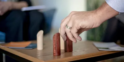 Eine Hand bewegt Holzfiguren auf einem Brett.