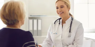 Arztgespräch über Demenz, Frau im Arztkittel