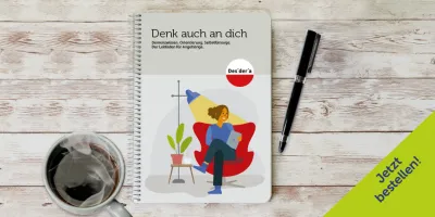 Broschüre 'Demenz neu sehen' von Desideria Care auf Holztisch, daneben Tasse Kaffee und schwarzer Stift.