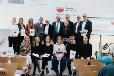 Gruppenfoto von 15 Personen in einem hellen Veranstaltungsraum, einige halten Urkunden oder Auszeichnungen in den Händen, im Hintergrund Logos der Stiftung Katholische Akademie.