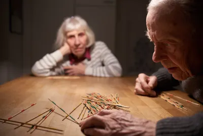 Älteres Paar spielt Mikado an einem Holztisch – gemeinsame Aktivität als Teil von Alltagsgestaltung und Beziehungspflege bei Demenz