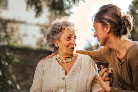 Eine ältere Dame und eine jüngere Frau unterhalten sich glücklich und lächelnd