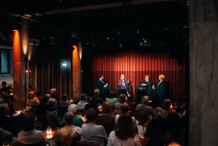 Blick auf die Podiumsdiskussion der Veranstaltung Mit Demenz leben, die Familie im Fokus: Auf der Bühne sitzen Moderator Maximilian Maier, Désirée von Bohlen und Halbach, PD Dr. Jens Benninghoff sowie Stefanie Wagner-Fuhs. 