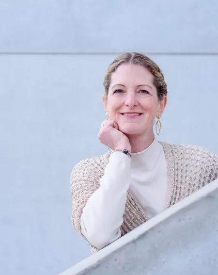 Desideria Familien-Coach, lächelnde Frau lehnt auf einem Geländer