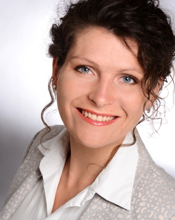 Frau mit dunklem Haar lächelt in die Kamera