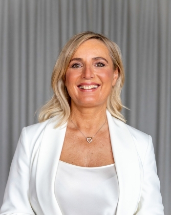 Lächelnde Frau in weiß vor grauem Vorhang